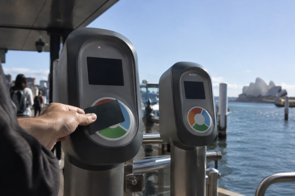 Opal card readers on a Sydney ferry wharf with a card hovering over the sensor