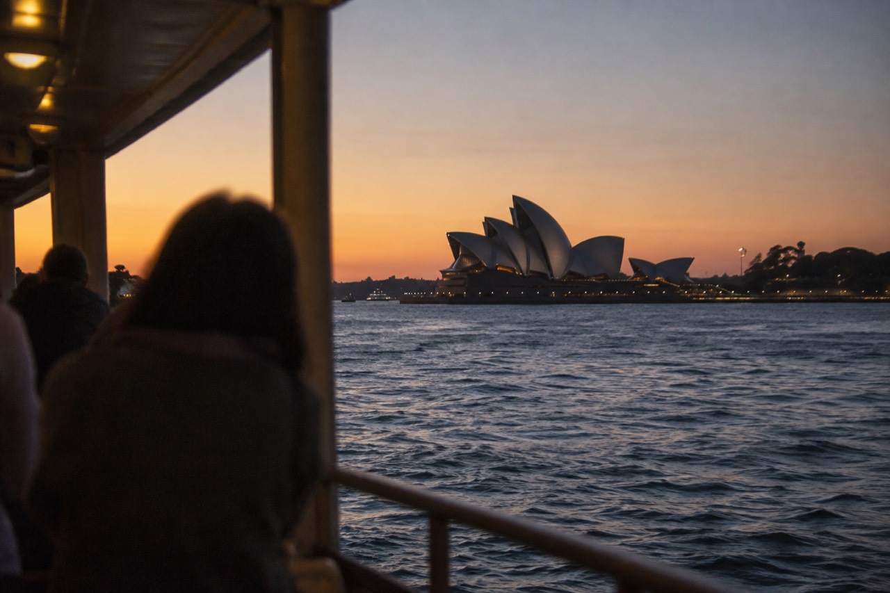 The white sails of the Sydney Opera House at dusk seen across Circular Quay