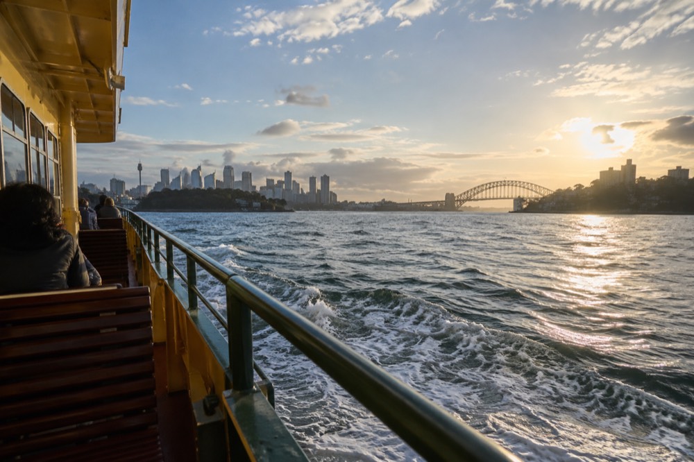 Ferry crossing Sydney Harbour toward the Manly skyline in late afternoon light