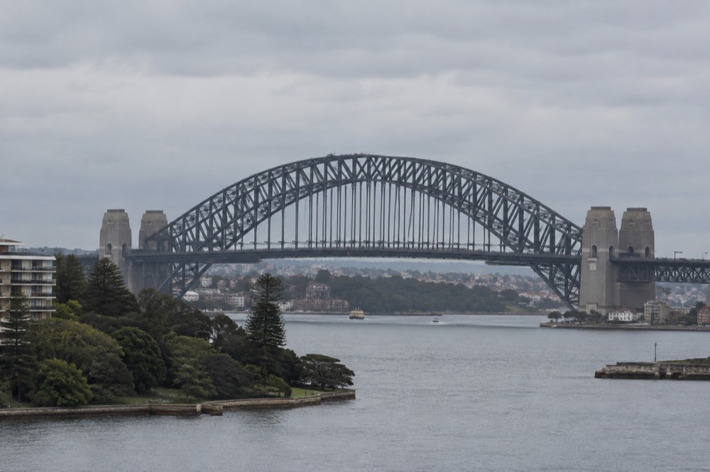 The upper arch of Sydney Harbour Bridge with climbers in grey suits attached to a safety rail