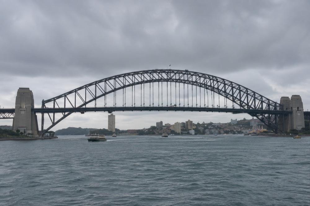 The upper steel arch of Sydney Harbour Bridge with climbers in grey suits attached to a safety line