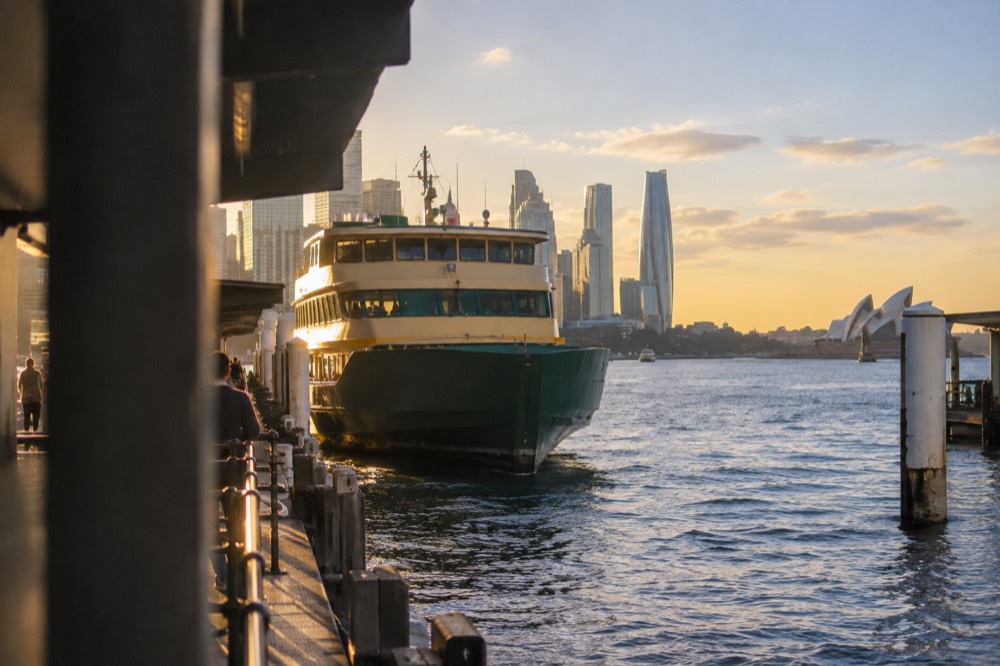 A Sydney ferry at Circular Quay wharf with the city skyline behind it