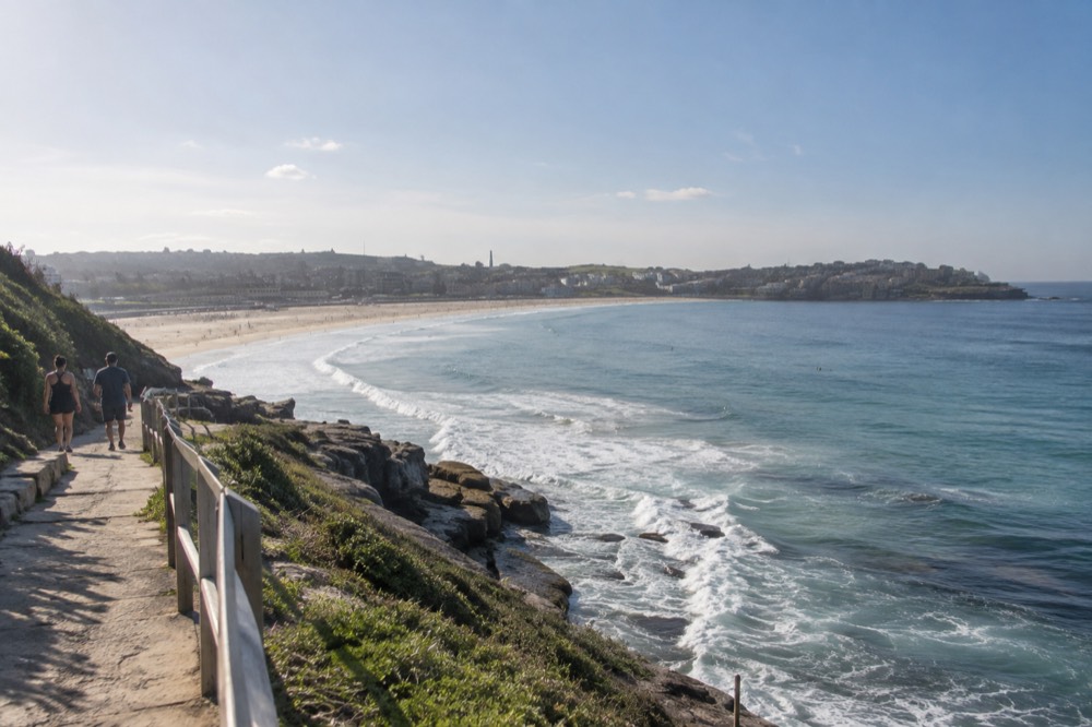 Sandstone cliffs and a curved sandy beach on the Bondi to Coogee coastal path on a clear morning