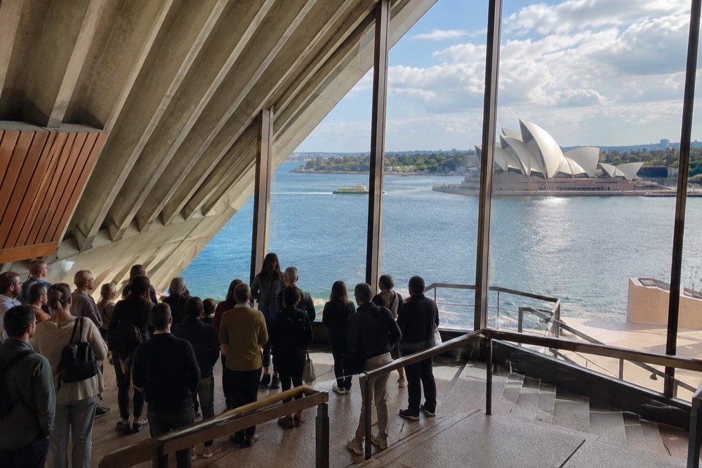 Tour group gathered in a Sydney Opera House foyer beneath the angled white ceilings