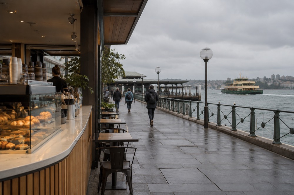 A laid-back Sydney cafe counter with pastries under glass and a coffee machine