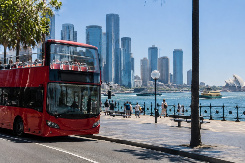 A hop-on hop-off sightseeing bus parked near Circular Quay with the Sydney skyline behind it