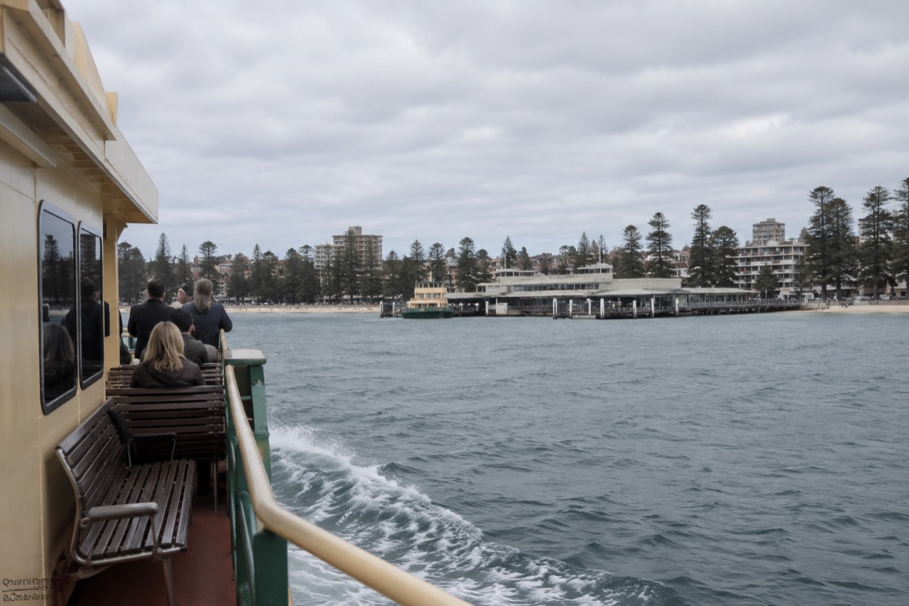 A Sydney ferry crossing sparkling harbour water with Manly ferry wharf ahead