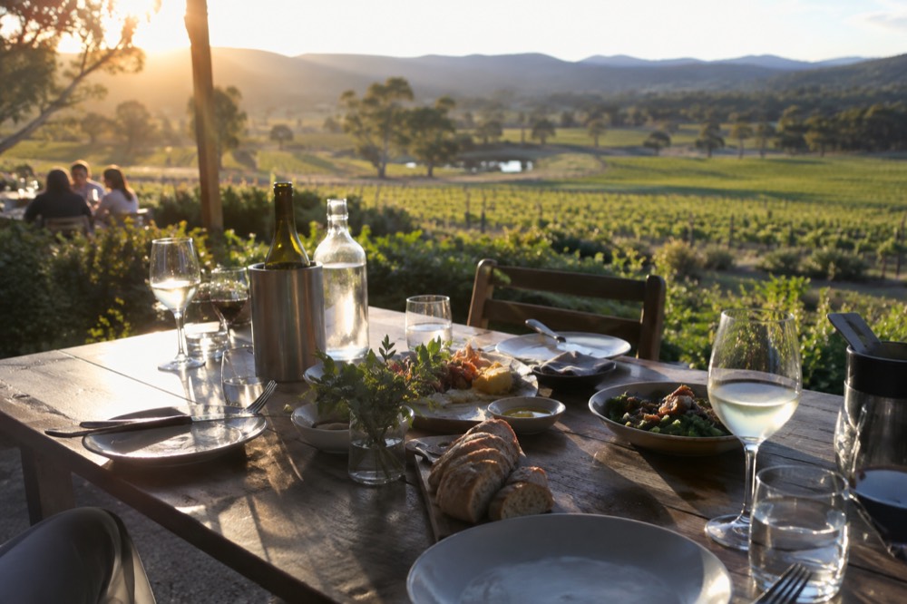 An outdoor table set for lunch overlooking vineyards and distant hills