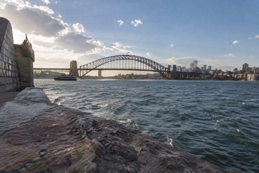 Sydney Harbour Bridge and city skyline seen across the water on a clear afternoon