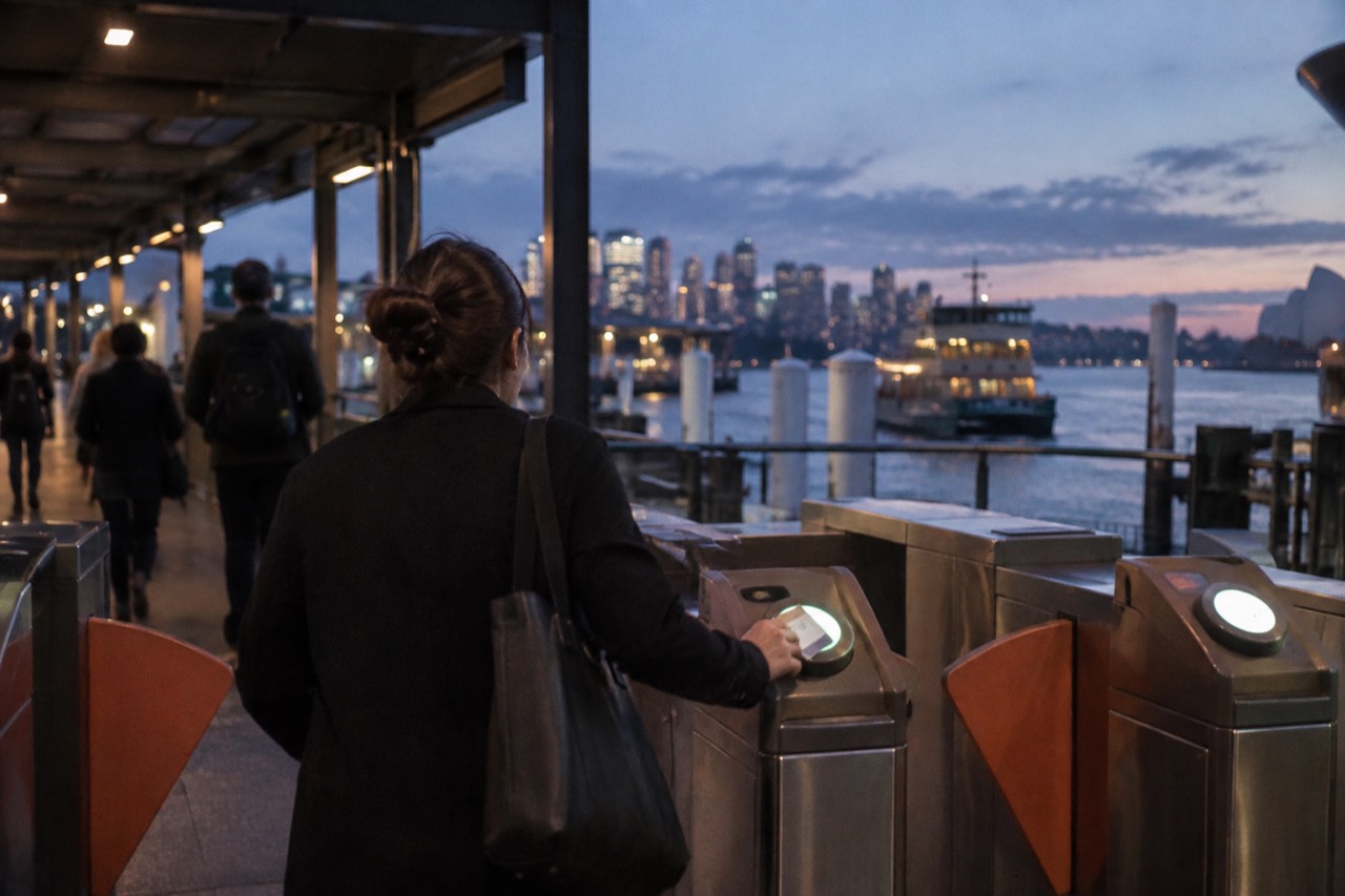 A commuter tapping a contactless card on an Opal reader at a Sydney train station gate