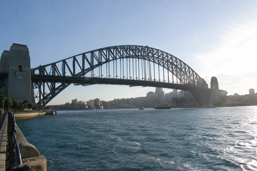 The upper arch and lattice of steel girders on the Sydney Harbour Bridge seen from below, with a clear sky above