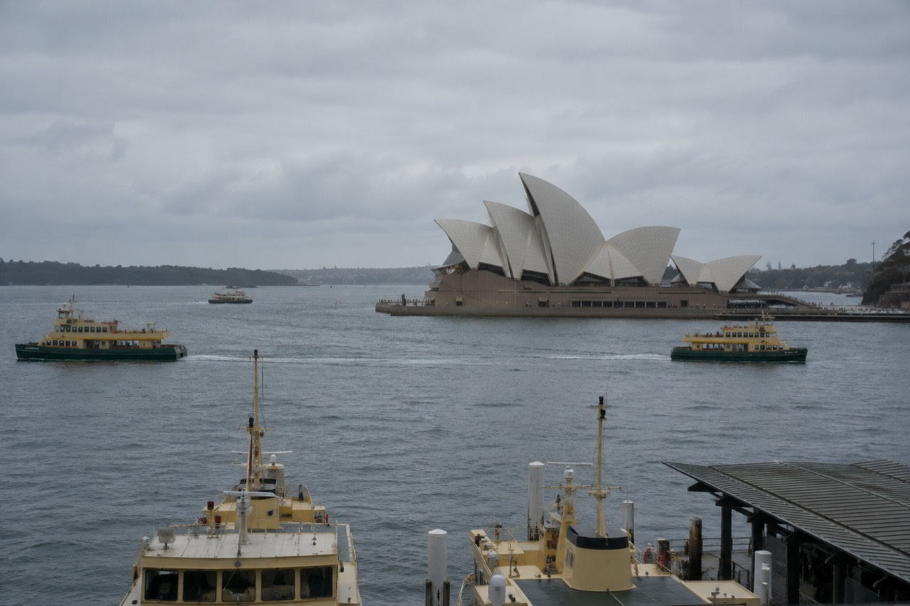 Sydney Opera House sails seen across the water with ferry masts in the foreground