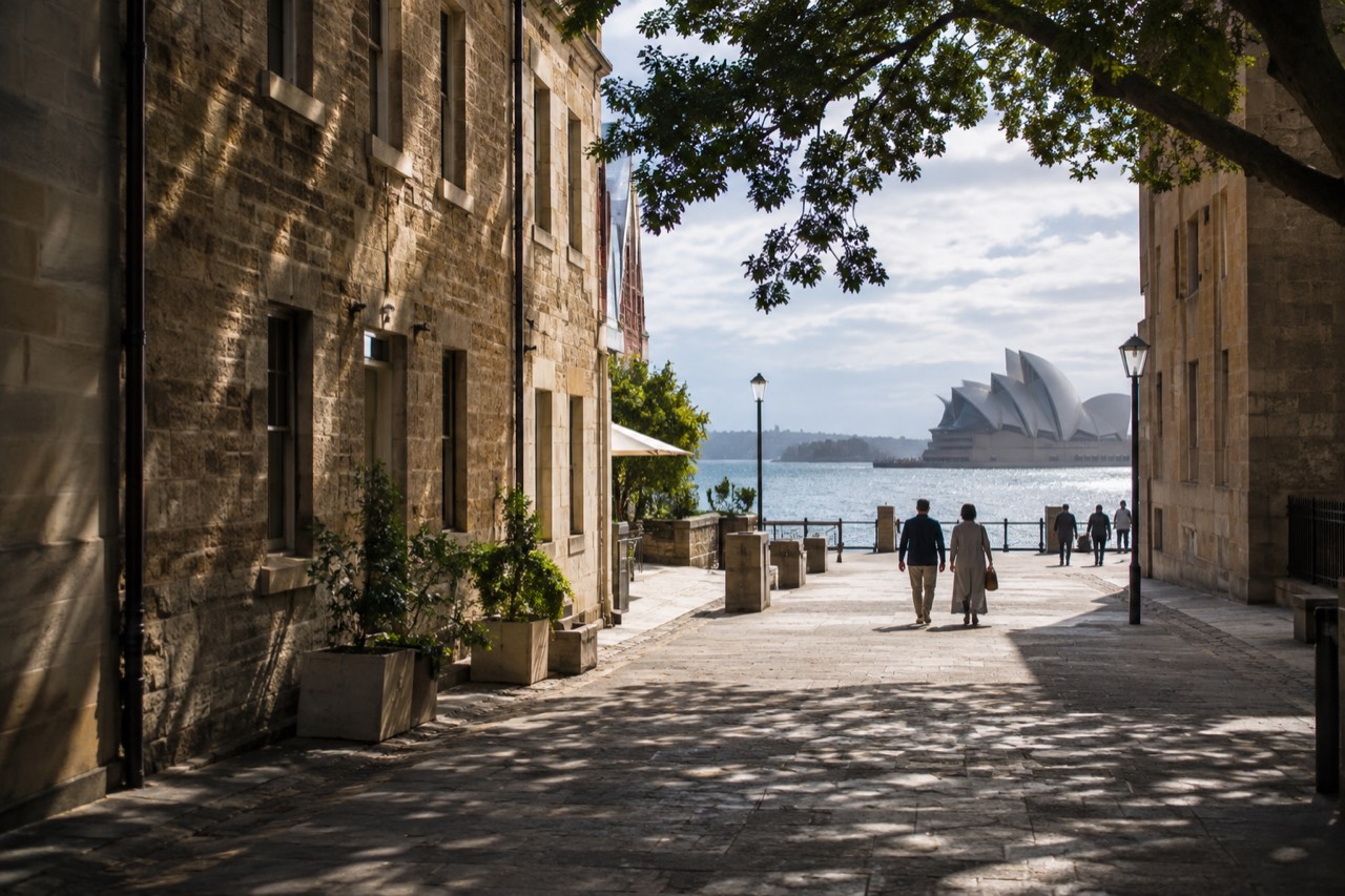 A wide sandstone pedestrian lane in The Rocks with the harbour beyond