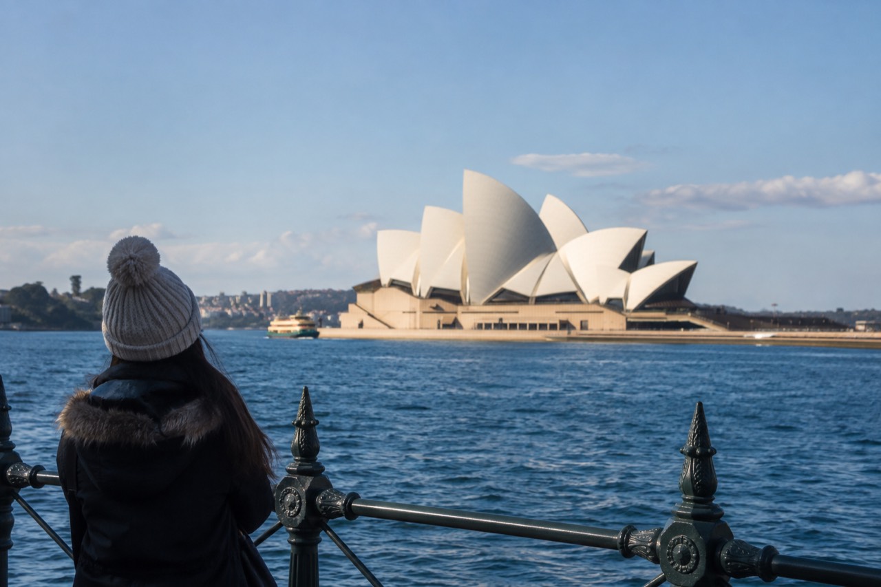 White sail-shaped roofs of the Sydney Opera House against a blue harbour sky