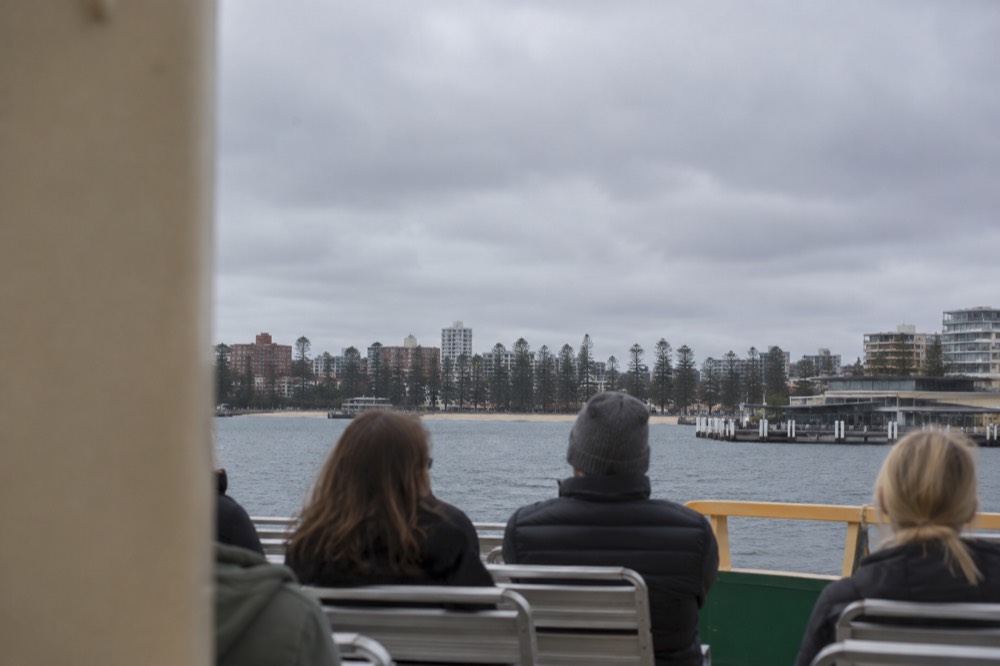 Passengers on the open upper deck of a ferry as it approaches Manly wharf