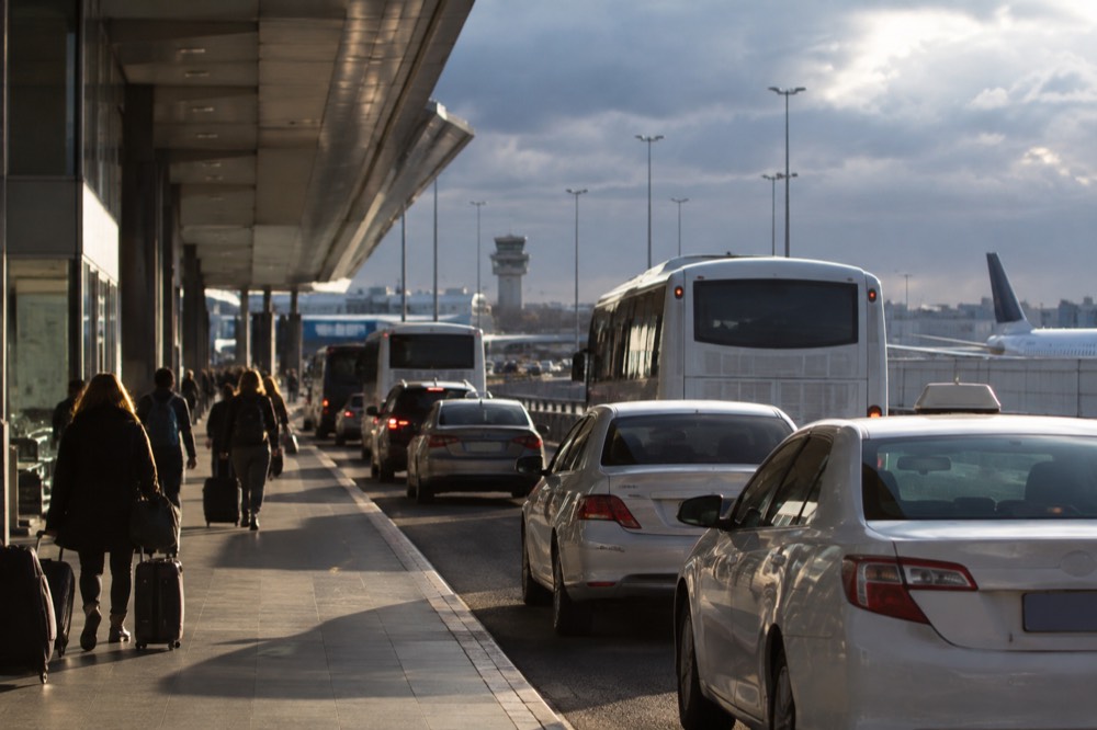 Buses and taxis waiting at a kerb outside an airport terminal building