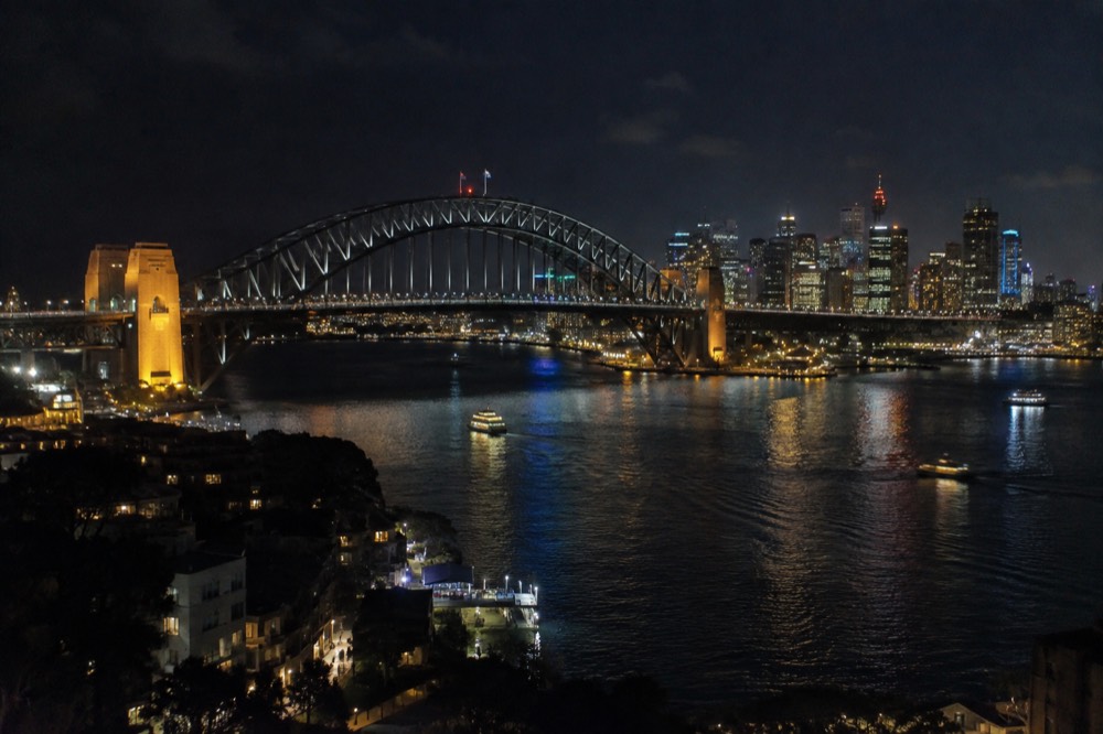 The Sydney Harbour Bridge at night with the city skyline lit behind it