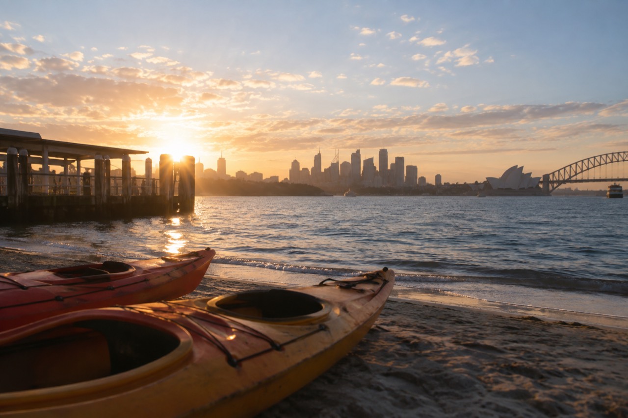 Dawn light over Sydney Harbour with kayaks resting on a quiet beach