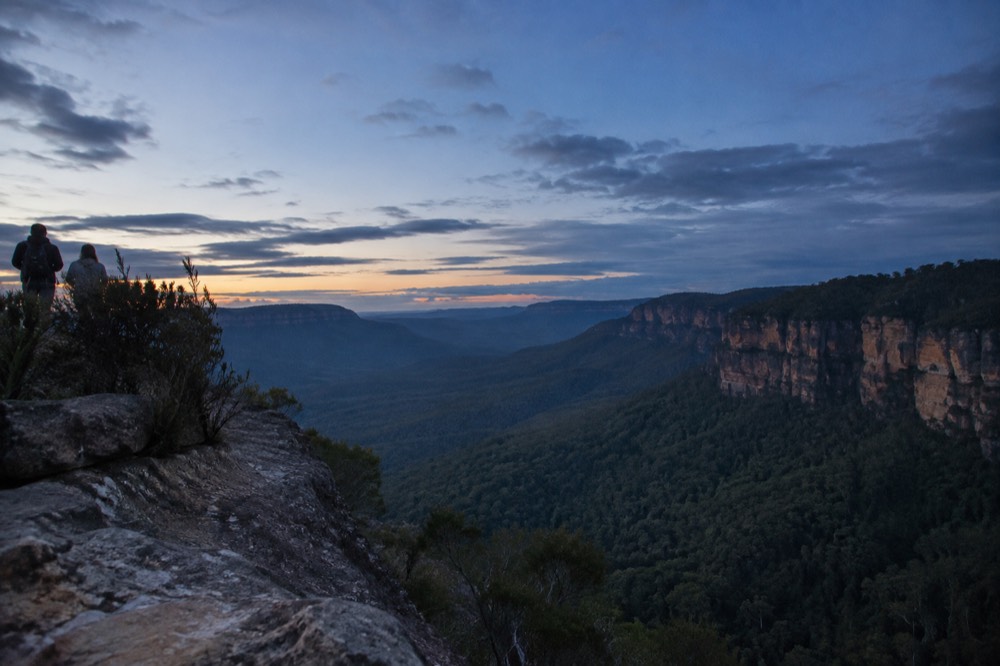 Sandstone cliffs and forested valley in the Blue Mountains under a wide sky