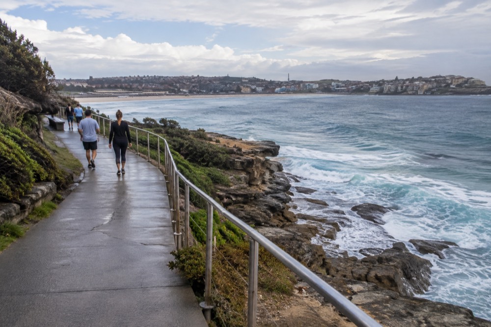 A paved clifftop path curving along a headland with the ocean on one side