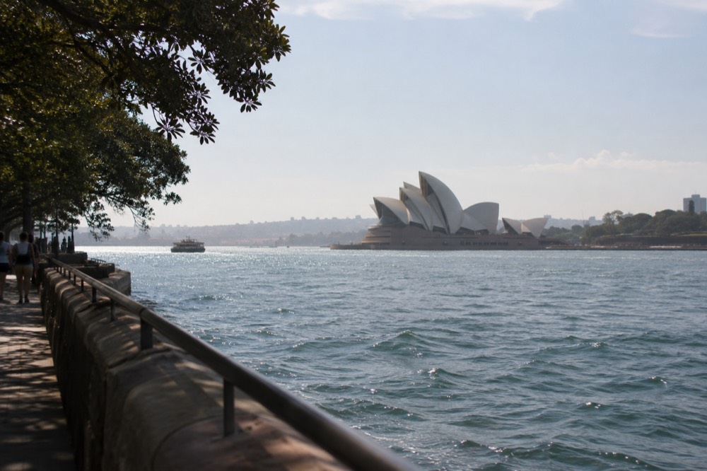 The Sydney Opera House sails seen across the water from a harbour walkway