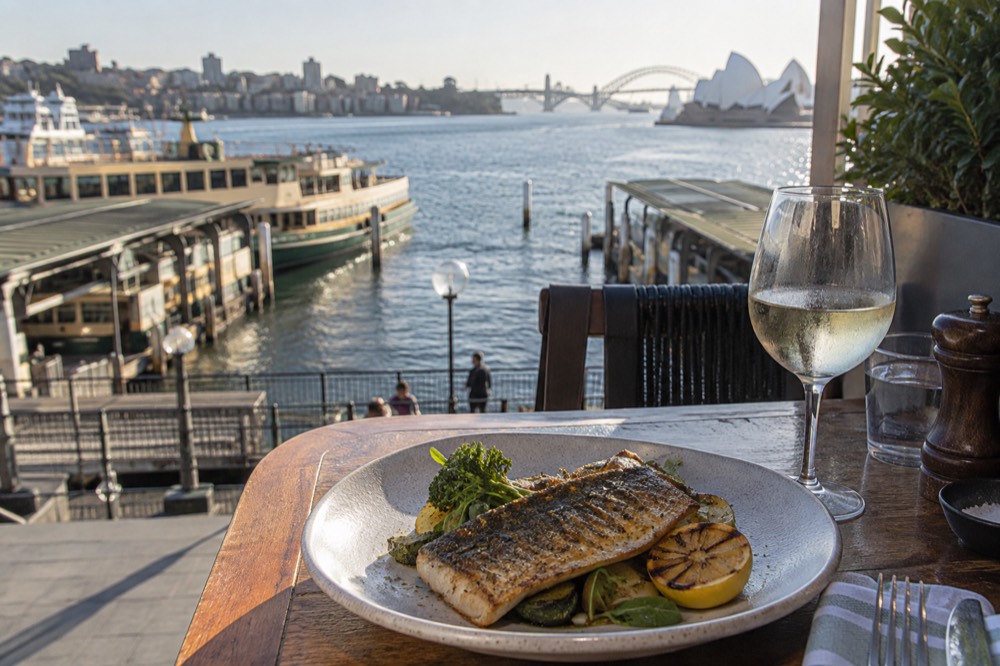 A plate of grilled barramundi with lemon served at an outdoor harbour restaurant