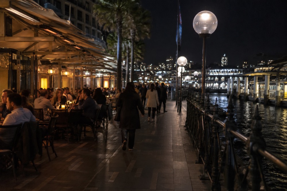 A busy suburban Sydney restaurant strip at night with small eateries side by side