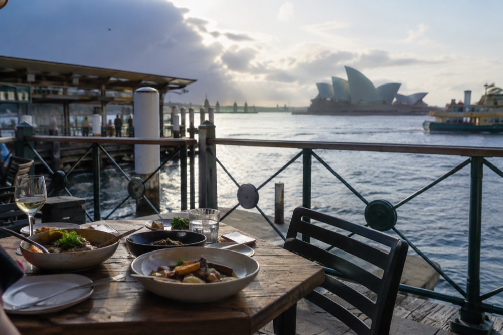 Dishes being shared on a small wooden table in a modest neighbourhood eatery