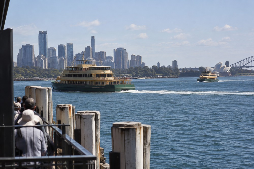 Ferry boats crossing Sydney Harbour with the city skyline behind them on a mild afternoon