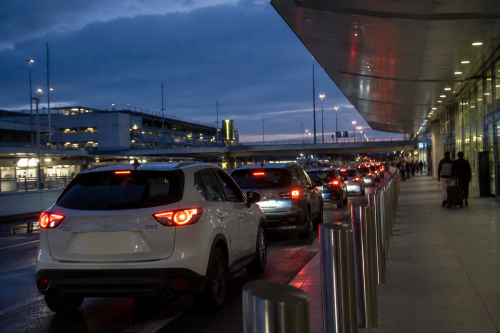 Taxis and rideshare cars queued in a covered pickup lane at an airport terminal.