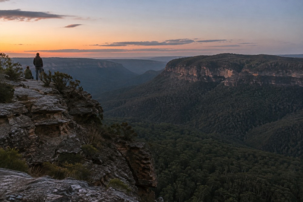 Sandstone cliffs and forested valleys of the Blue Mountains under a wide sky