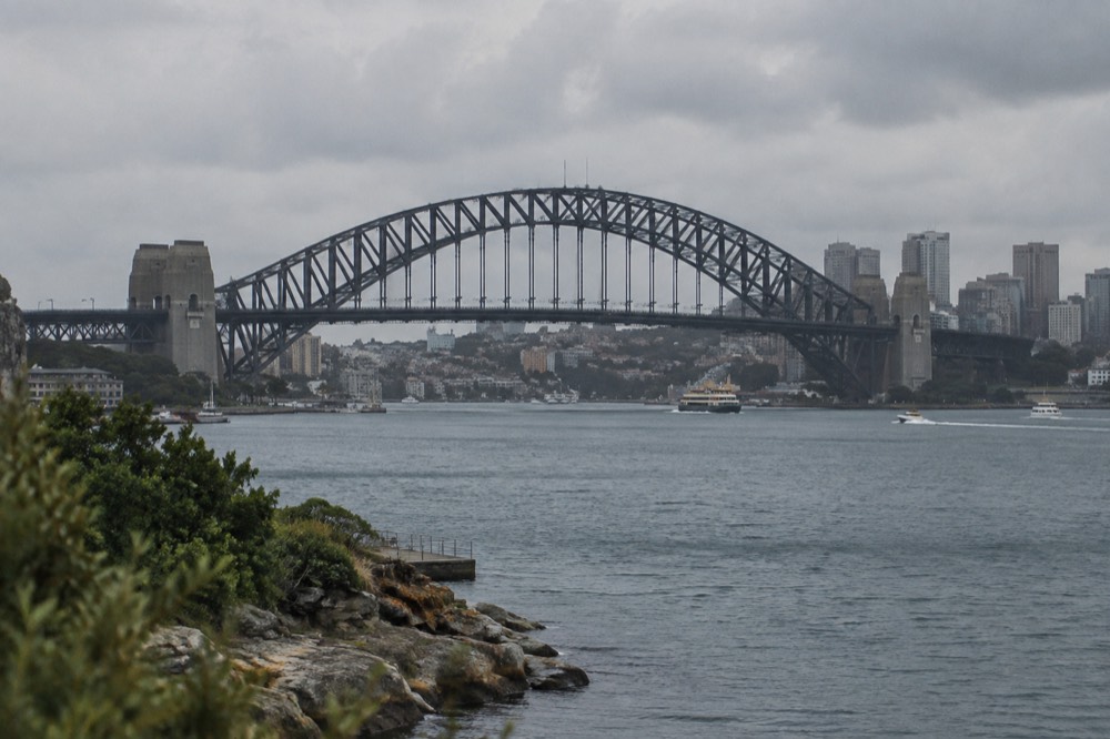 The steel arch of the Sydney Harbour Bridge rising above the water with the city skyline behind it