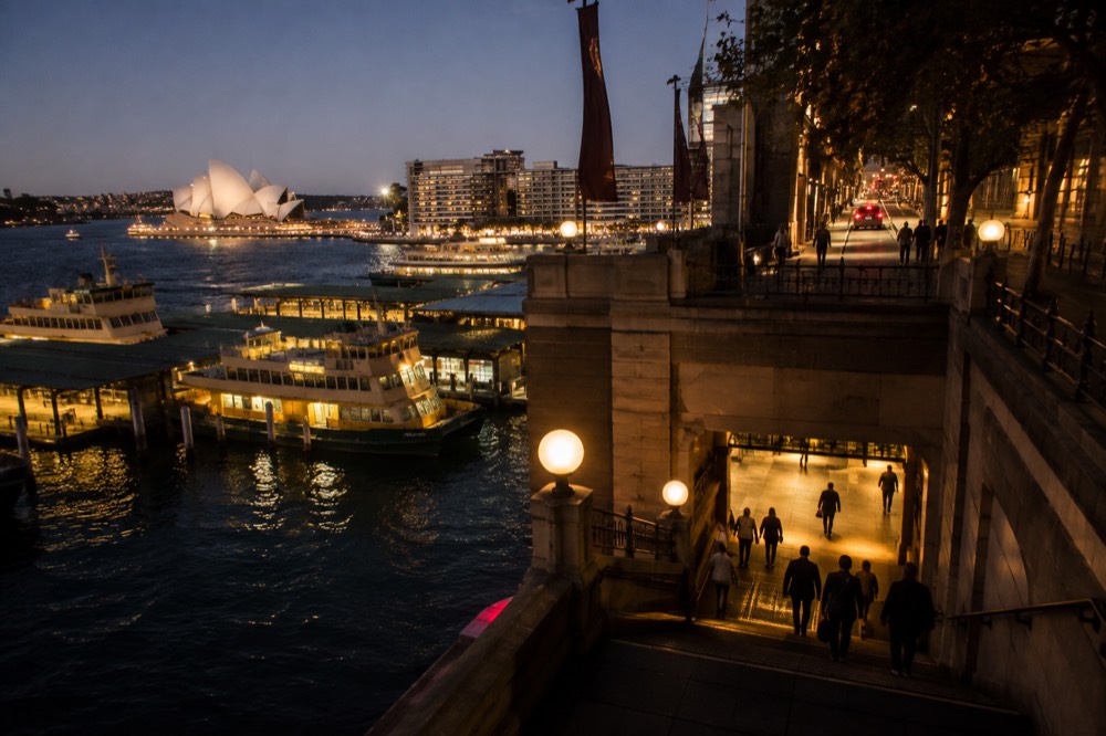 A Sydney train station entrance lit up at night with a quiet street above it