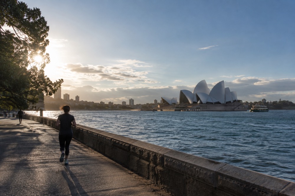 Sunlight over Sydney Harbour with the Opera House sails brightly lit against a clear sky