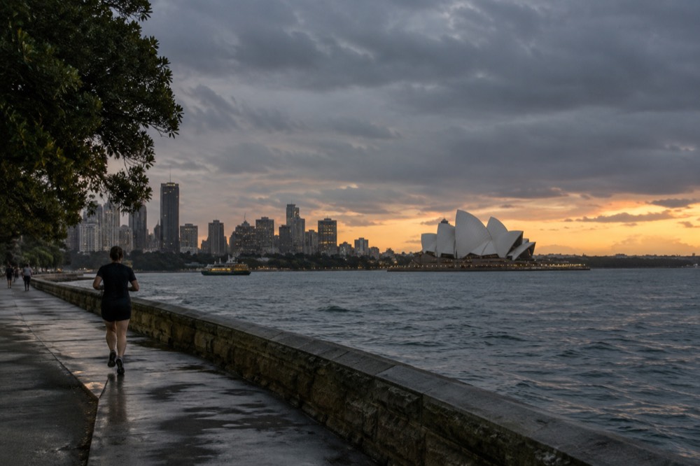 Grey rain clouds over Sydney Harbour with the Opera House and city skyline in soft light