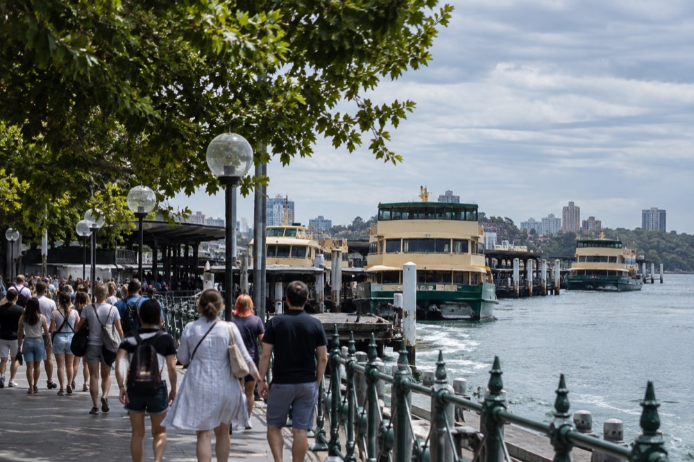 Crowded Circular Quay promenade on an overcast summer afternoon with ferries at the wharves