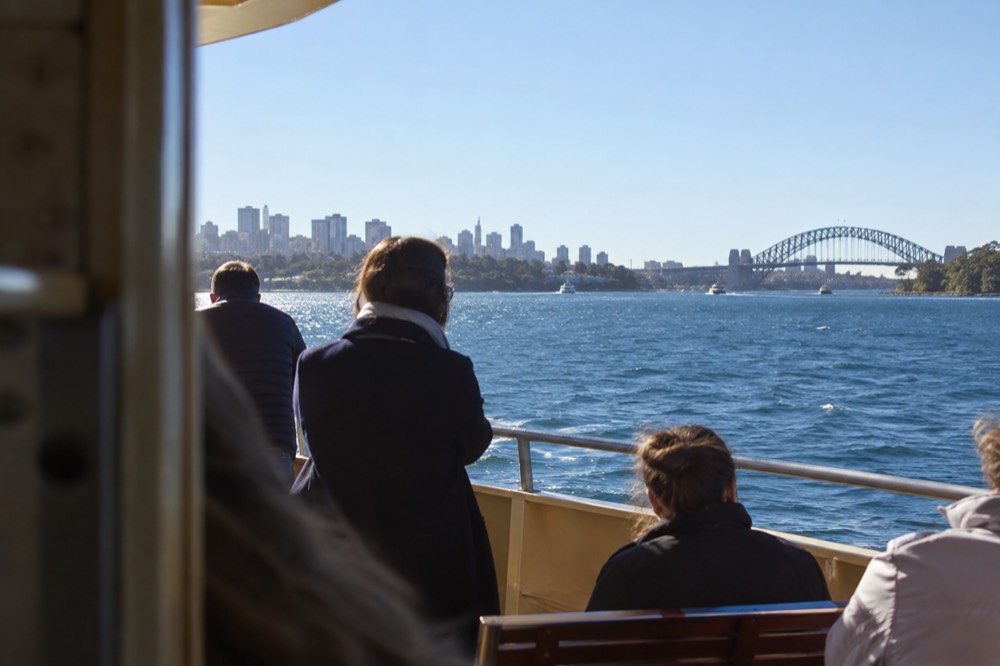 The open decks of a Sydney ferry on a clear winter afternoon with the harbour and headland in the background