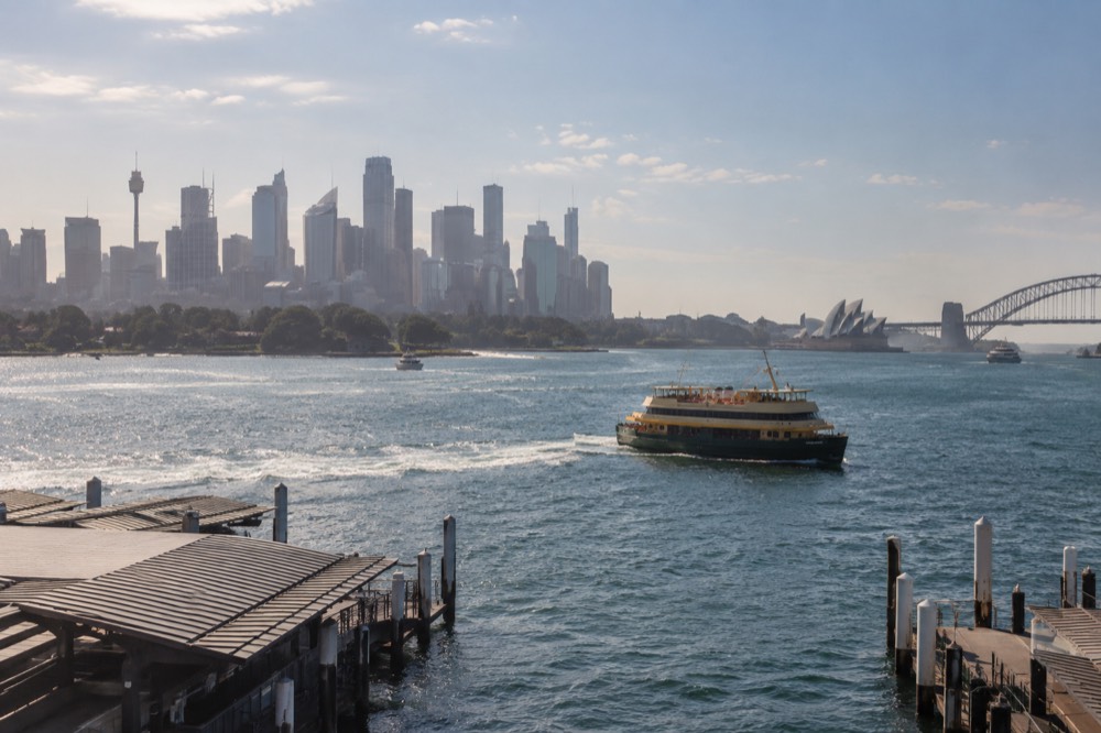 A ferry crossing Sydney Harbour with the city skyline behind it on a clear morning
