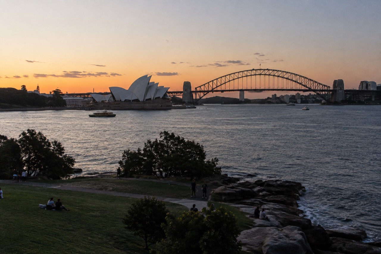 Sydney's harbour foreshore on a clear afternoon with the Opera House and Harbour Bridge in view