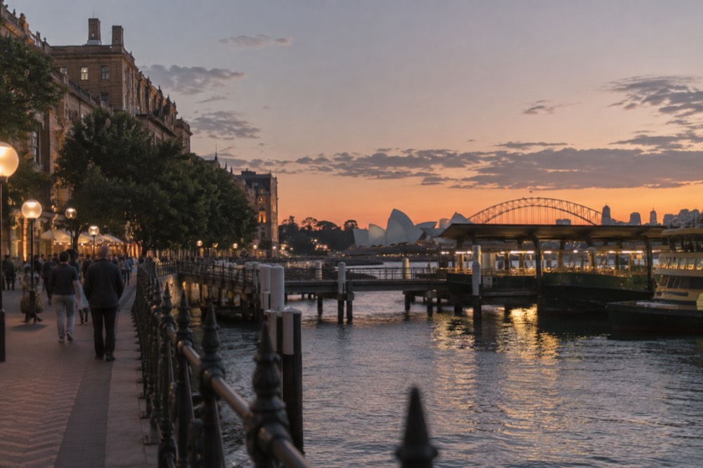 Historic sandstone terrace buildings on a hillside street overlooking Sydney Harbour