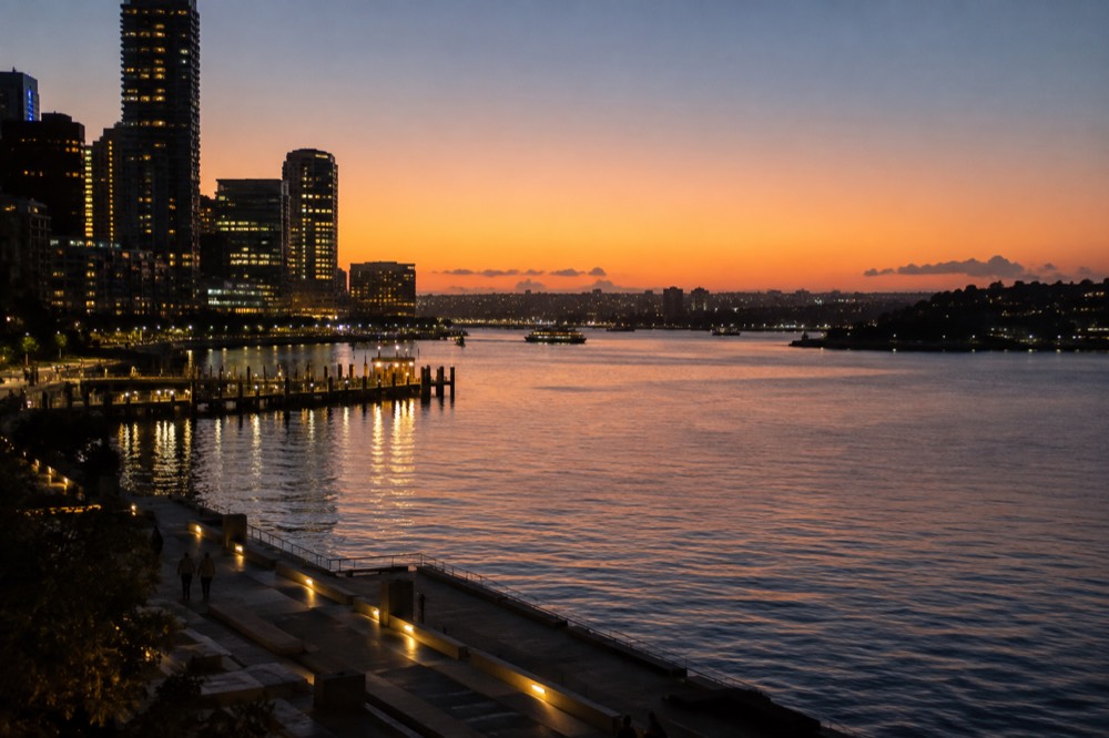 City skyline and harbour lights reflected in dark water after sunset