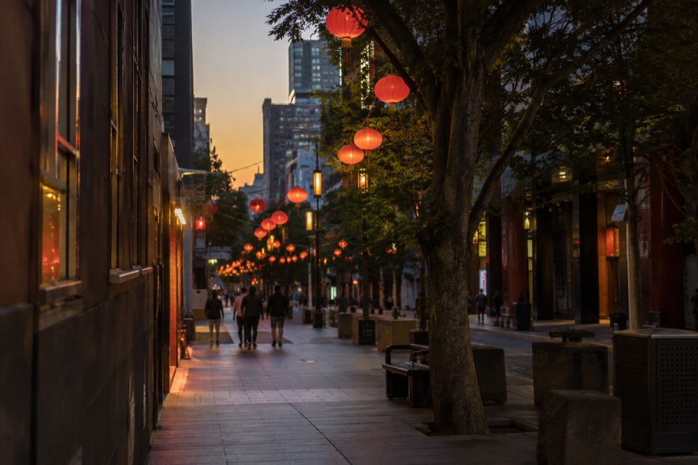 Lanterns strung across Dixon Street at dusk with restaurant signage glowing below