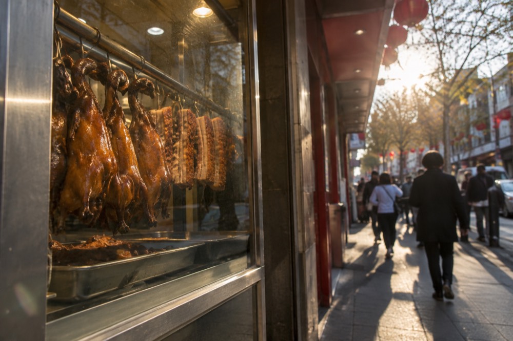 Restaurant window with roast ducks and pork hanging behind glass in Chinatown