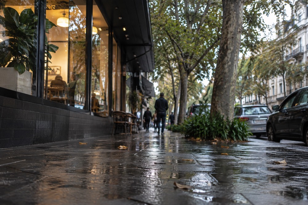 Rain-slicked Darlinghurst Road footpath reflecting shop lights