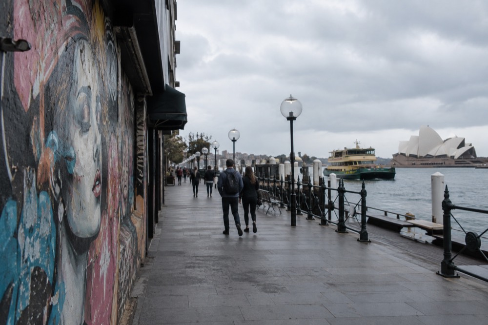 A shopfront wall covered in layered street art posters and murals