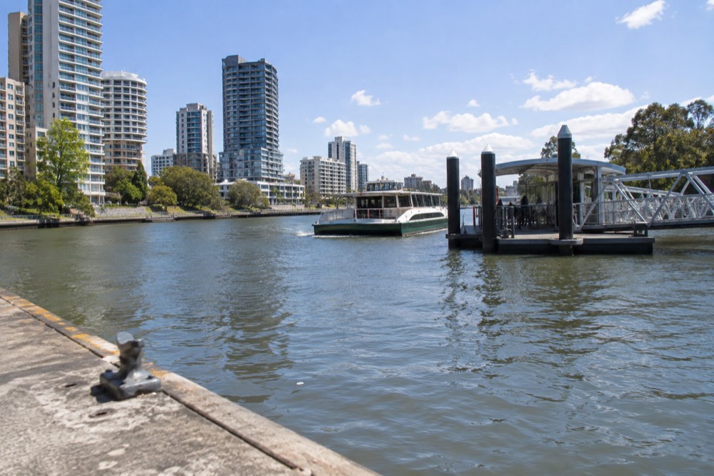 Parramatta River at midday with ferry wharf and apartment towers along the bank