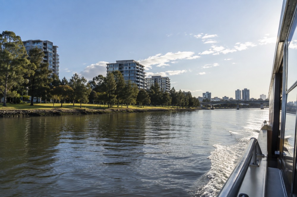 Parramatta River ferry travelling past parkland and apartment buildings