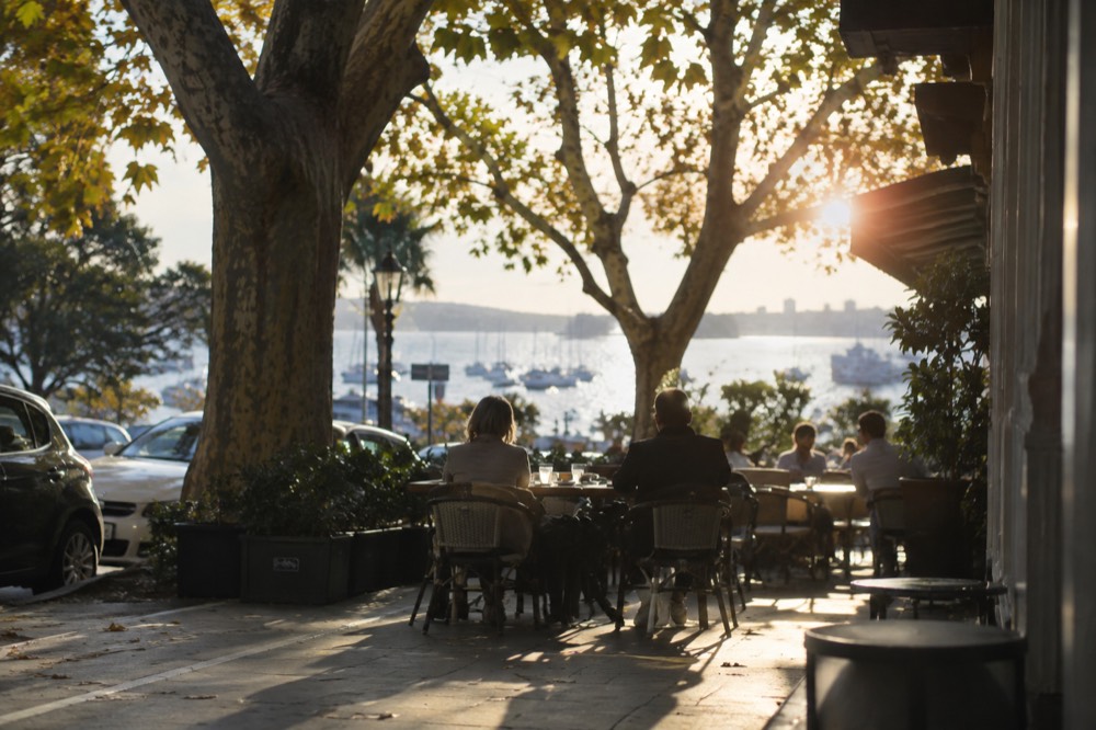 Outdoor tables under plane trees at a Potts Point corner cafe