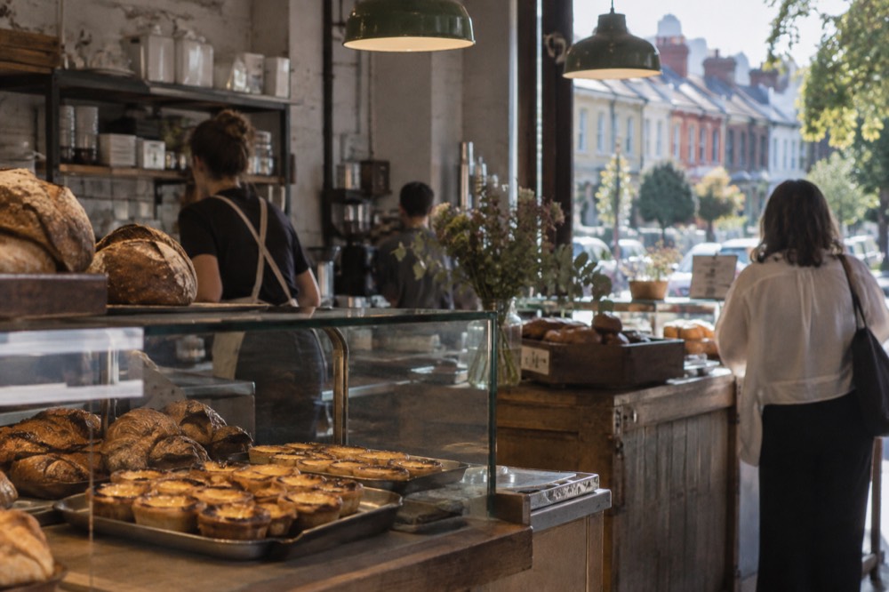 A bakery counter with trays of custard tarts and bread loaves