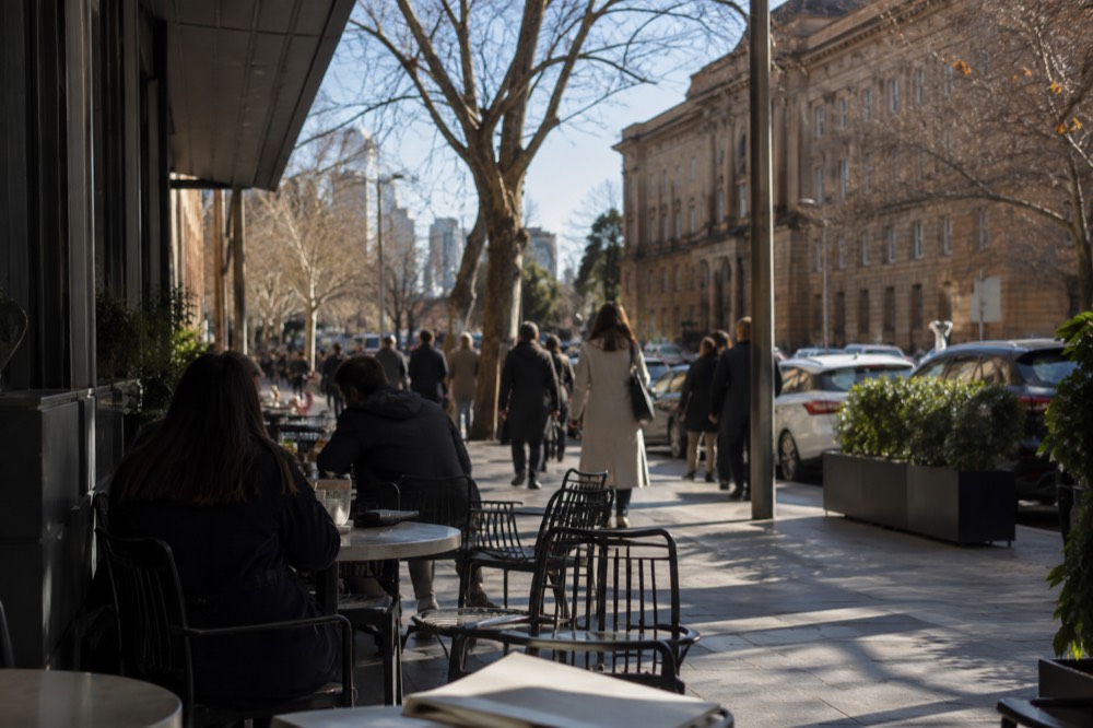 Cafe tables on a city street near the Australian Museum with lunchtime crowds